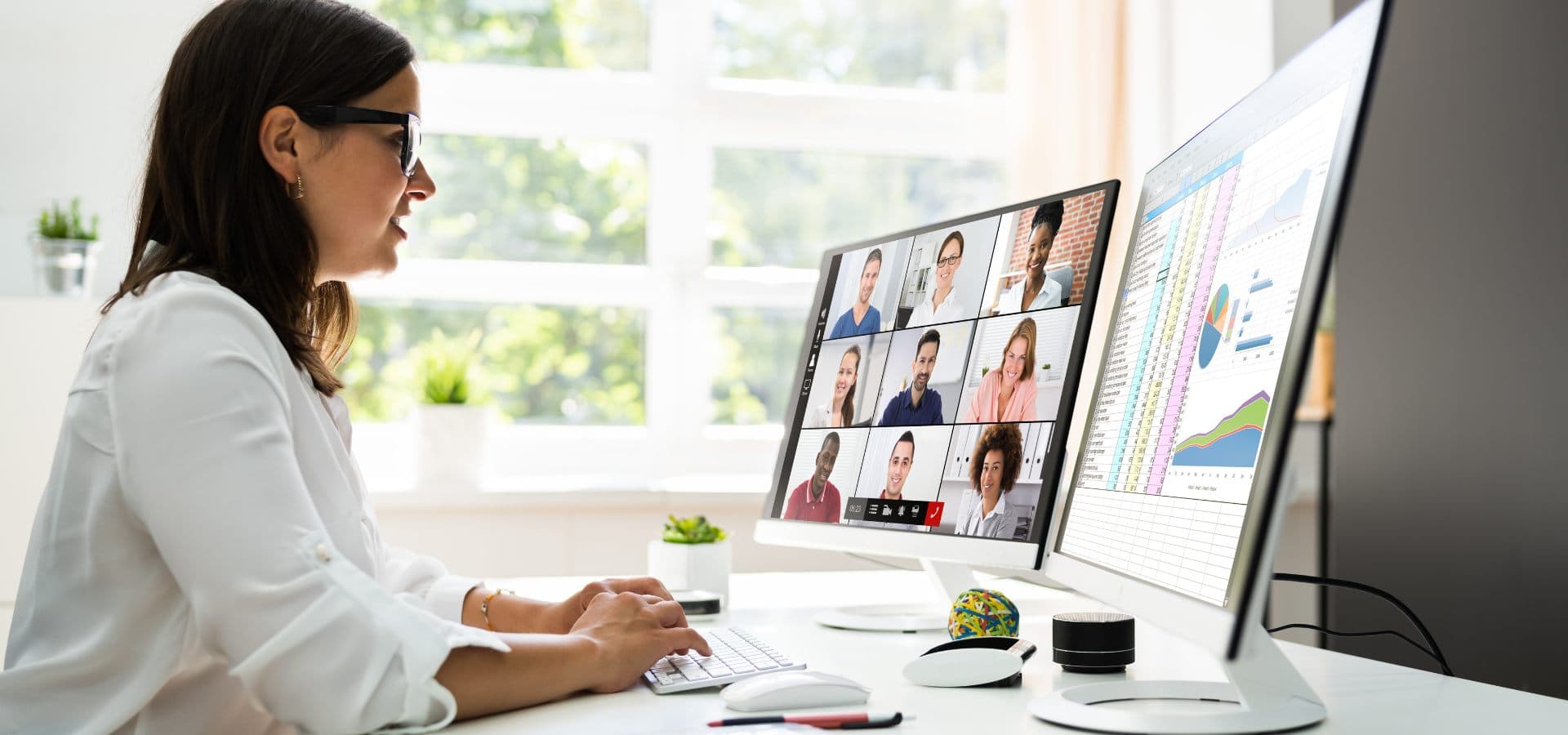 Profesional en videoconferencia empresarial junto a un monitor con dashboards financieros